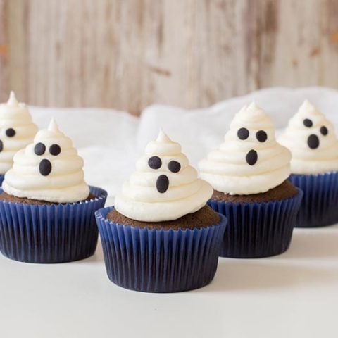 5 completed chocolate ghost cupcakes on white tabletop.