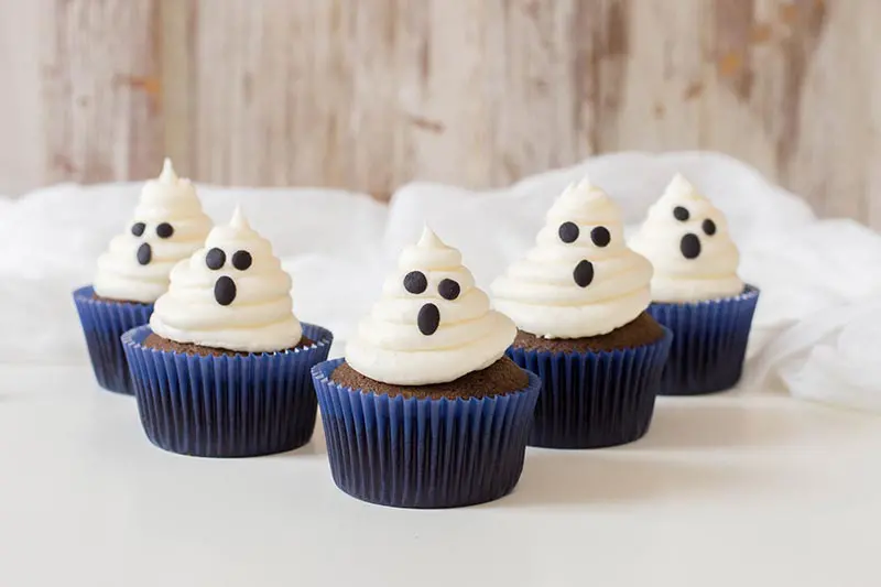 5 completed chocolate ghost cupcakes on white tabletop.