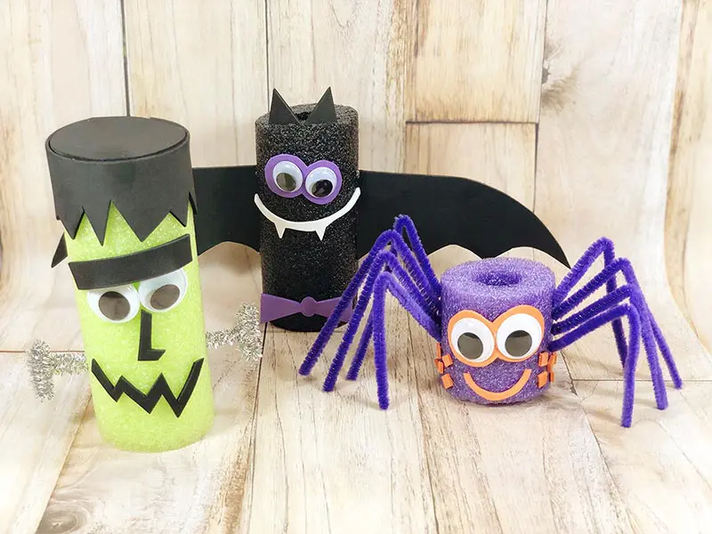Frankenstein monster, bat, and spider pool noodle crafts standing on a light board background.