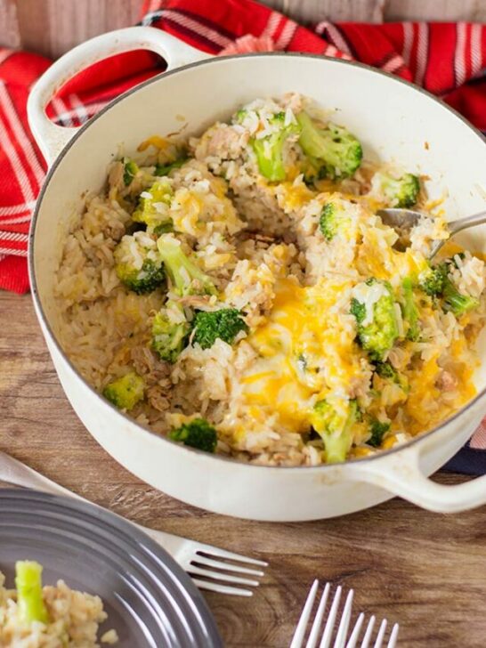 Cheesy tuna rice in white cooking pot on table with a red cloth