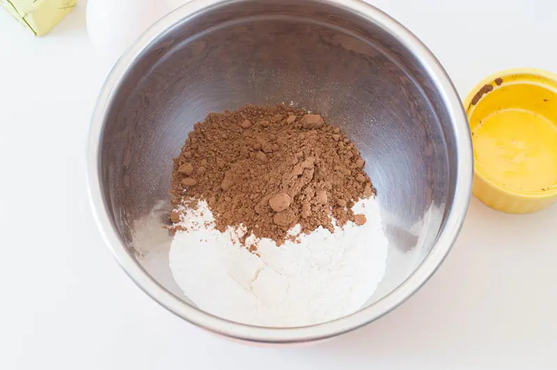 Flour, coca powder, and other dry ingredients in a silver mixing bowl