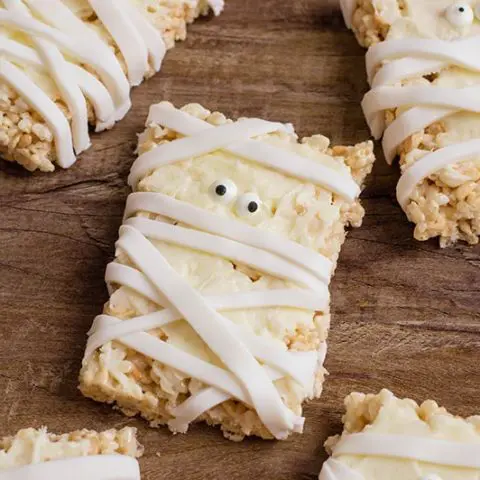 Close up of a few mummy decorated rice crispy treats on table.