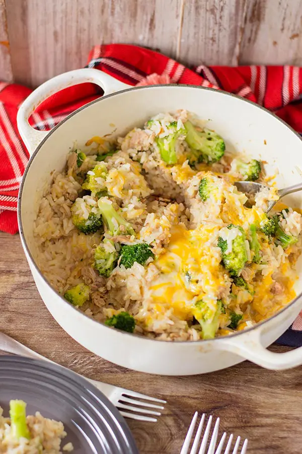 Cheesy tuna rice in white cooking pot on table with a red cloth