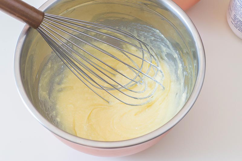 Whisk and cake batter in silver mixing bowl