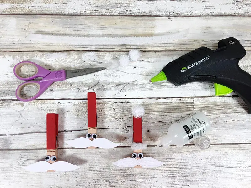 Attaching googly eyes and pom poms to clothespin with hot glue gun.