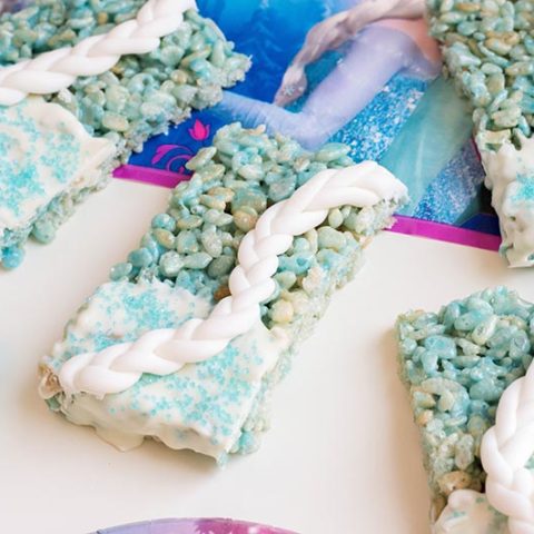 Close up of finished Elsa rice crispy treats on white table with Frozen themed napkins.