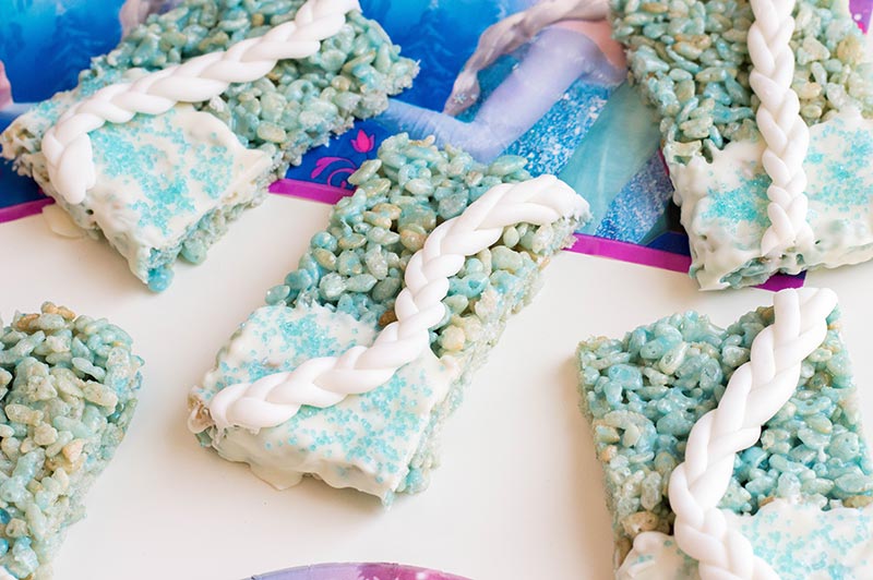 Close up of finished Elsa rice crispy treats on white table with Frozen themed napkins.
