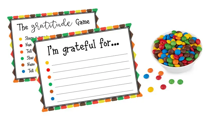 Gratitude Game cards on white background with white bowl of colorful round candies.
