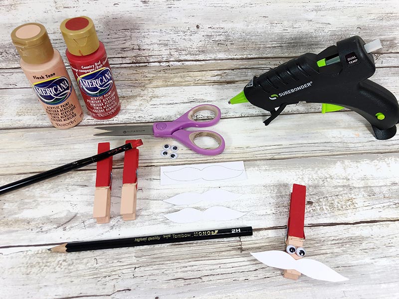 Craft supplies set out and showing how to paint clothespins.