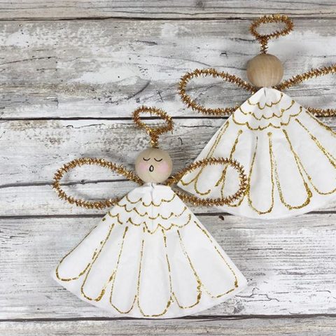 Two finished angel ornaments, one with painted face and one with blank face on white wood background.