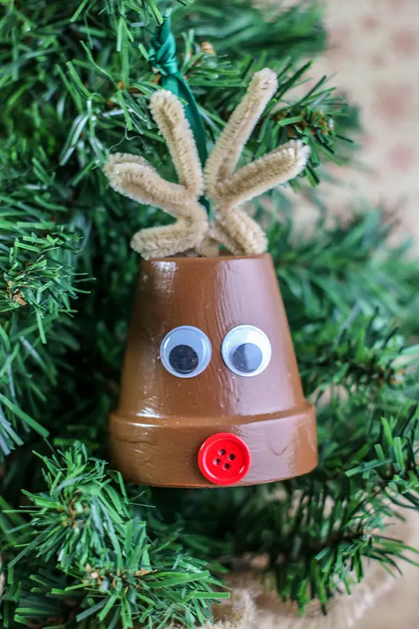 Completed reindeer ornament made with a small clay pot hanging on a small Christmas tree.