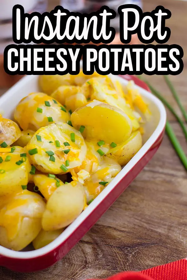 Close up of serving dish with cheesy potatoes on brown table top.