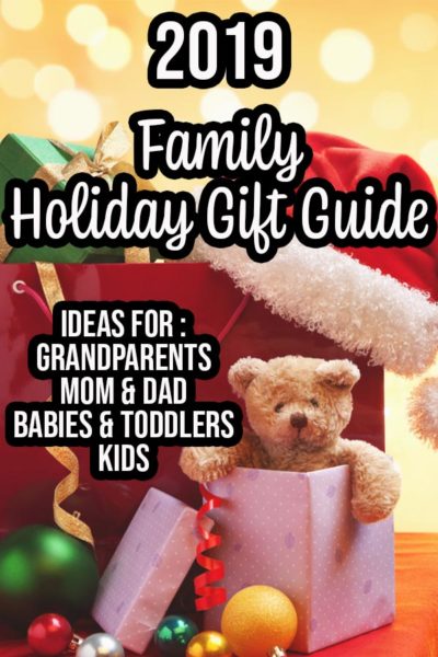 Pile of presents, teddy bear popping out of one gift, and a Santa hat on a table. Yellow bokah background and text overlay describing gift guide.