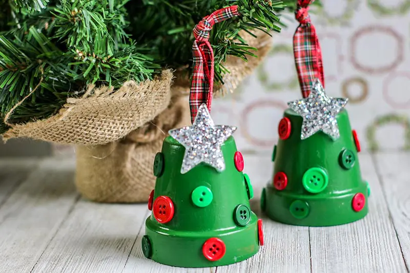 Completed clay pot Christmas Tree ornaments sitting side by side on table next to mini evergreen tree.