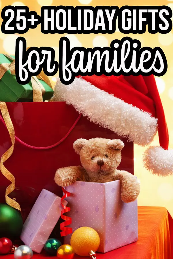 Pile of presents, teddy bear popping out of one gift, and a Santa hat on a table. Yellow bokah background and text overlay that says 25+ Holiday Gifts for families.