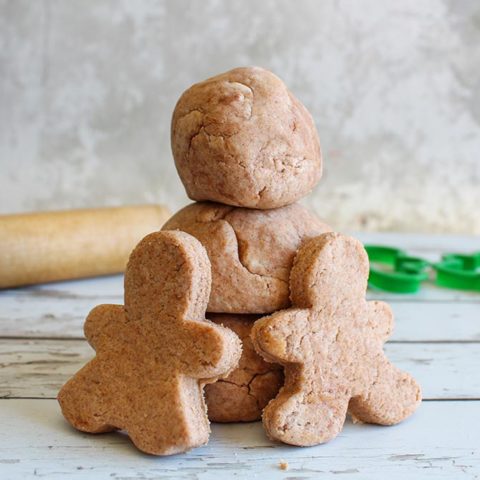 close up of gingerbread playdough gingerbread men cut outs and rolled into balls and stacked.