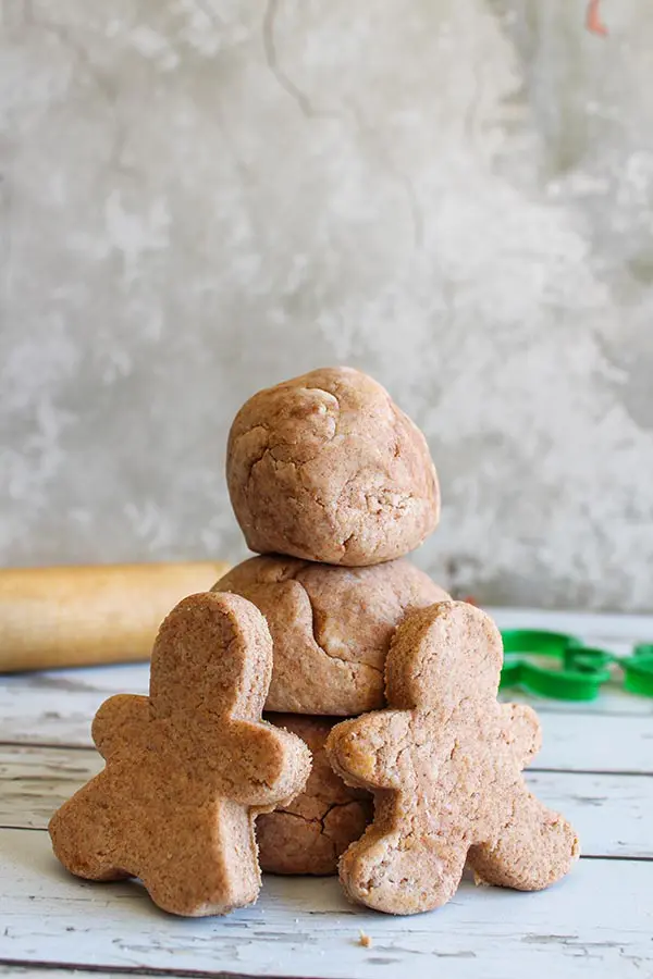 Brown playdough balls stacked up with gingerbread men cut out of playdough leaning against them.