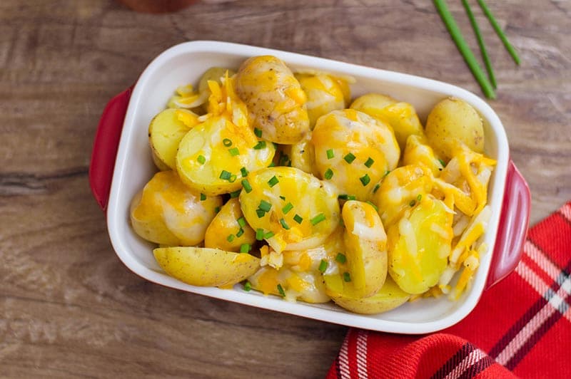 Overhead shot of small rectangular white and red serving dish filled with cheesy potatoes.