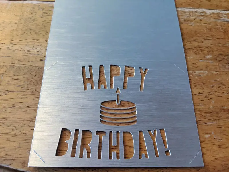 Thick shiny silver paper with the words happy birthday cut out.