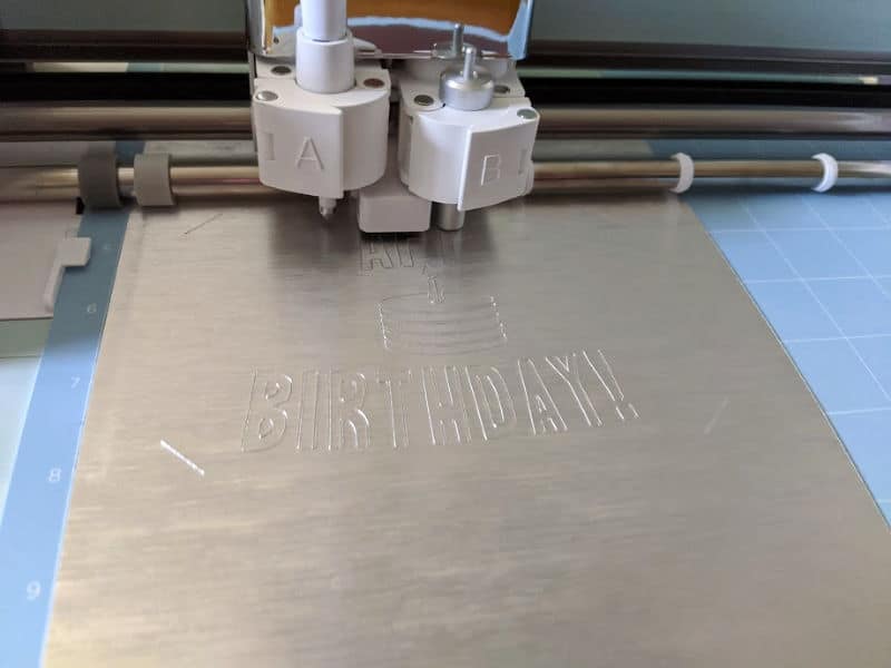 Cricut machine cutting happy birthday card using silver paper.