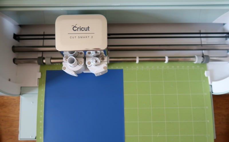 Blue iron on vinyl on green cutting mat loaded into Cricut Explore Air 2 machine.