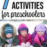 Three kids bundled up in winter gear laying on the snow and smiling.