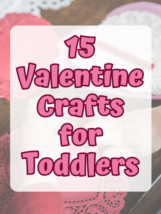 Pink text over a partially transparent white rectangle says 15 Valentine Crafts for Toddlers. Background shows little hands making a heart shaped craft.