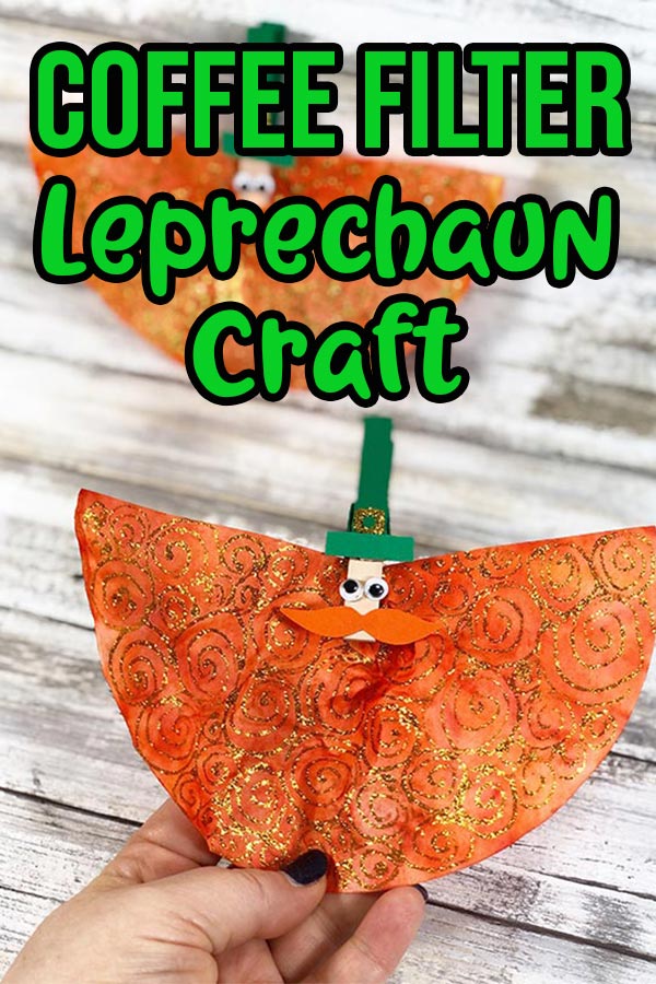 Woman's hand holding finished leprechaun craft and another laying in background. Text overlay with craft title.