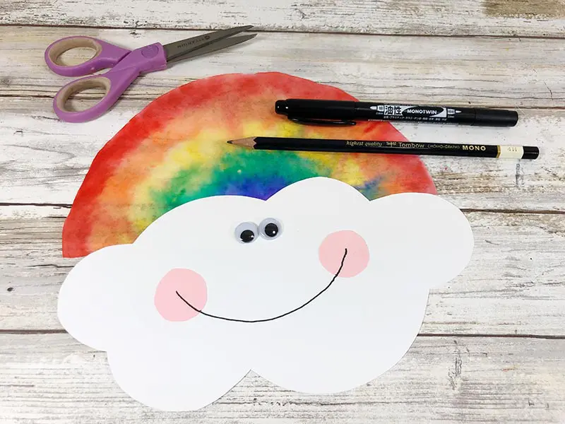 White cloud shape glued to rainbow coffee filter. Googly eyes and cute smile added to cloud to make a face.