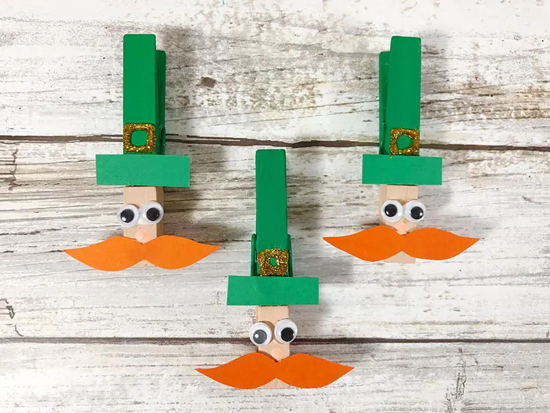Three leprechaun clothespin heads with orange mustaches.