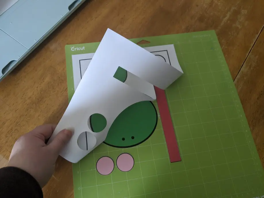 Pulling white cardstock off Cricut mat leaving frog craft pieces.