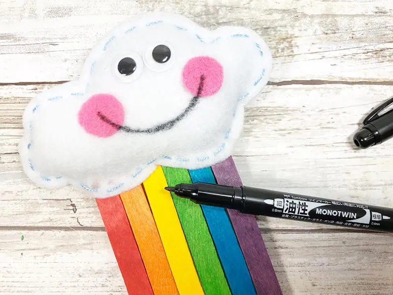Close up of stuffed felt cloud with googly eyes, pink cheeks, and hand drawn smile.