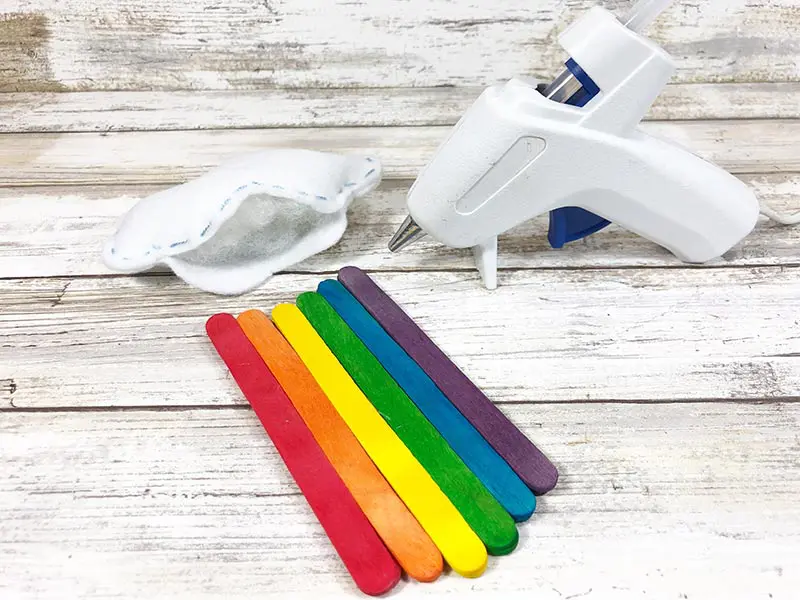 Gluing stuffed felt cloud to rainbow craft sticks.