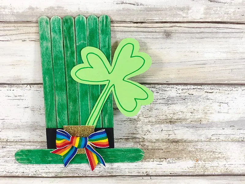 Overhead view of green top hat made with popsicle sticks and decorated with a paper shamrock.