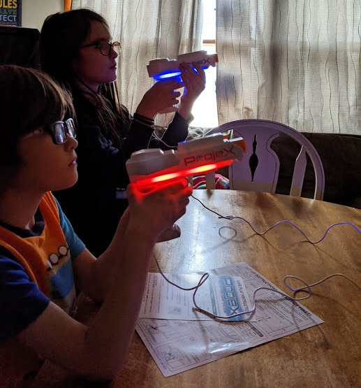 Boy and girl with ProjeX blasters. One is lit up with red and the other is blue.