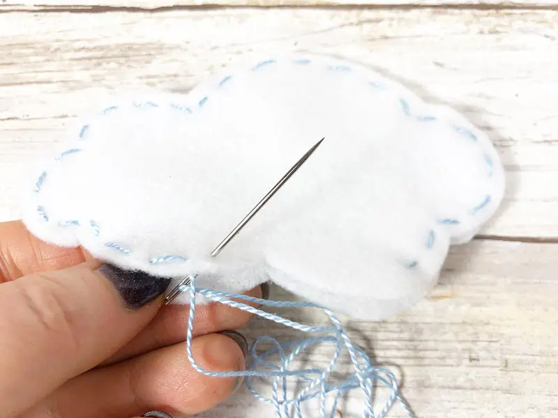 Using blue thread for running stitch around felt cloud.