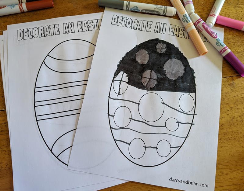 Printed Easter egg coloring sheets on table by markers. One egg is partially colored in.