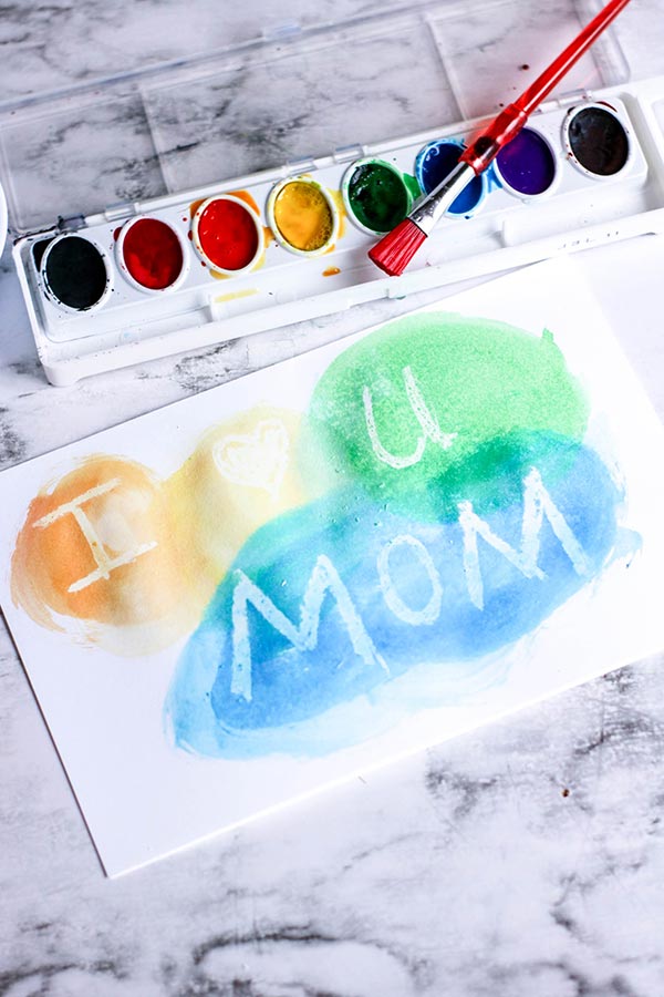 Painting with watercolors over white crayon reveals message or design.