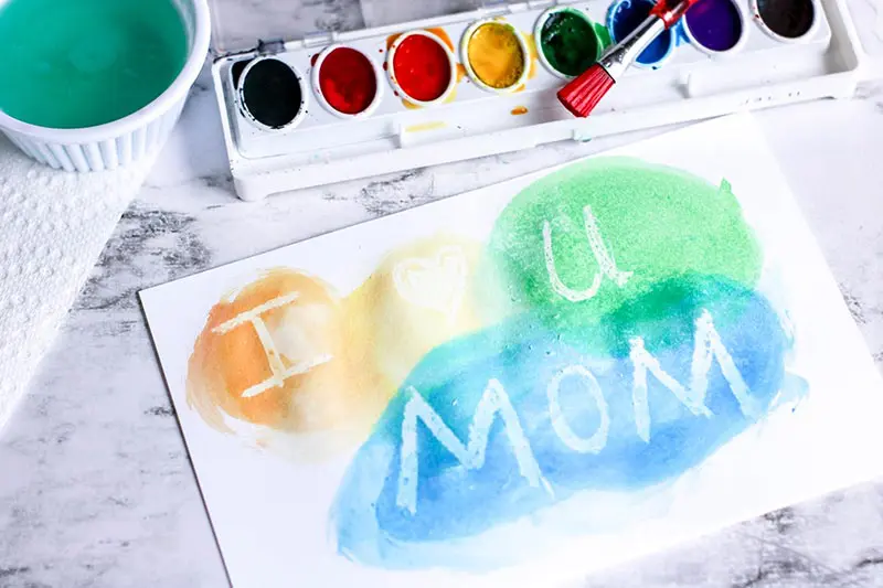 Yellow, green, and blue watercolor paints on card revealing I heart you Mom.