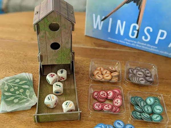 Bird feeder dice tower on table next to food tokens and Wingspan game box.