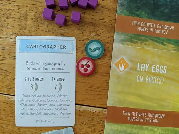 Cartographer bonus card laying on table next to player mat, food tokens, and purple wooden cubes.