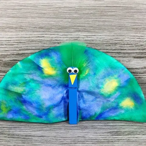 Close view of completely assembled coffee filter peacock craft project with gray wood background.