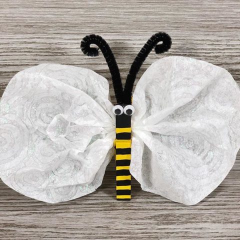 Close view of finished coffee filter and clothespin bee craft with gray wood background.