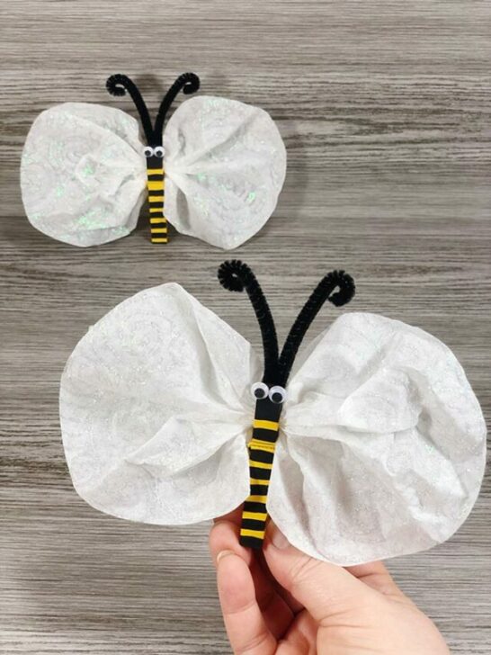 Hand holding up completed coffee filter bumble bee. Another finished bee is in the background.