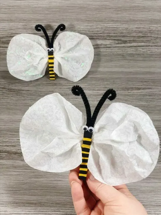 Hand holding up completed coffee filter bumble bee. Another finished bee is in the background.