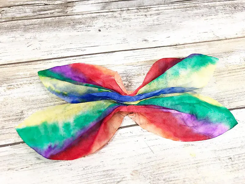 Colorful coffee filter with sides gathered into the center to shape the dragonfly's wings.