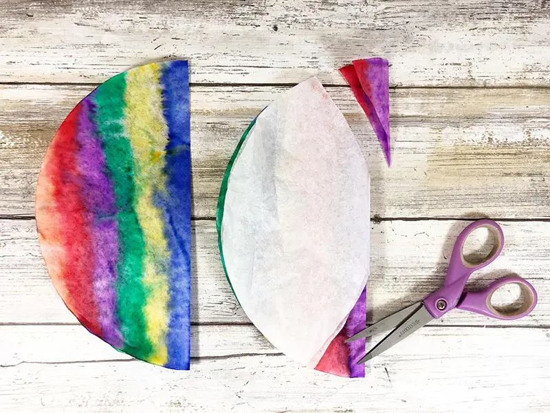 Colored coffee filter folded to demonstrate where to trim it.