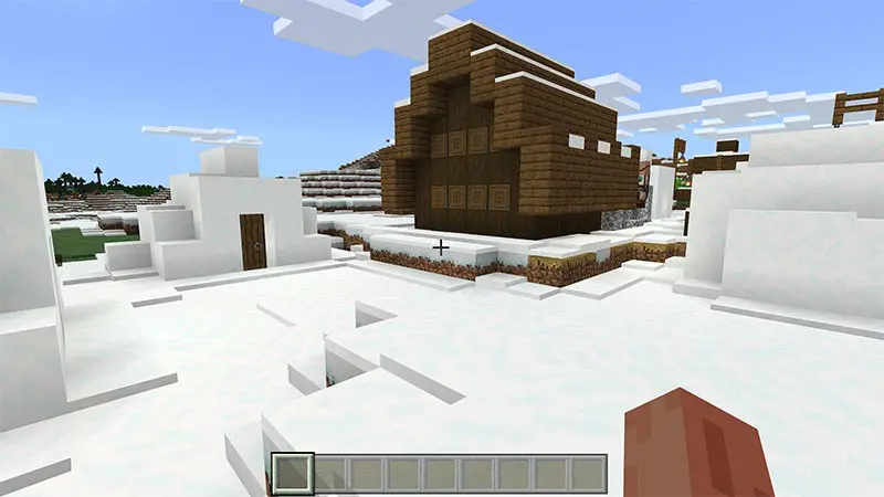 Minecraft in game screenshot of a snow covered village.