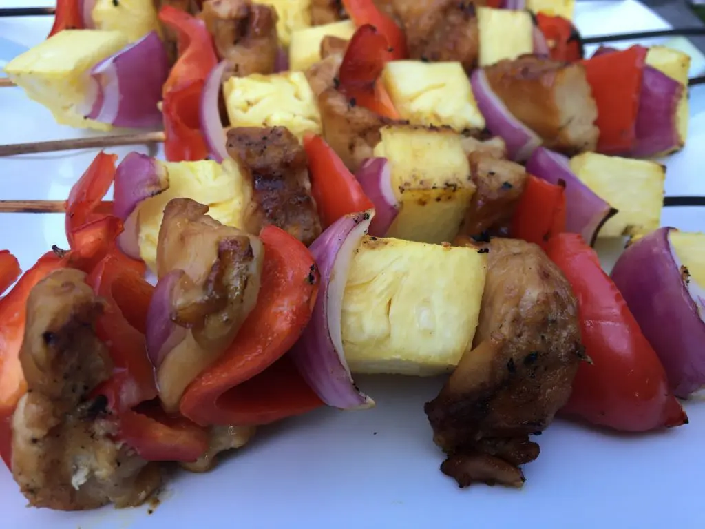 Close up view of cooked chicken shish kabobs with pineapple, red pepper, and red onion.