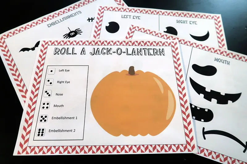 Blank pumpkin with dice key and other pages from printable game set on black table.